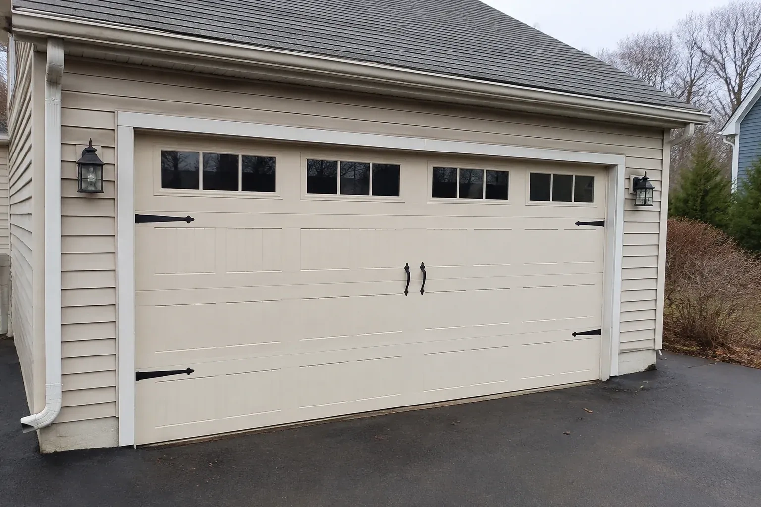 Cream carriage-house-style garage door with dark decorative hardware. — Carriage-House Garage Door Installation, Scugog